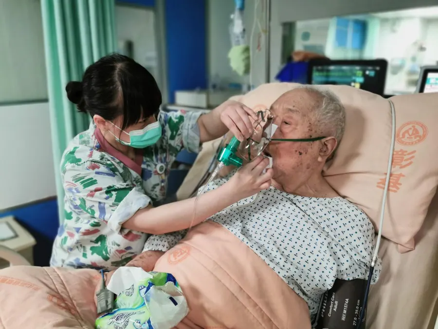 Nurse attending a patient on oxygen support at the bedside