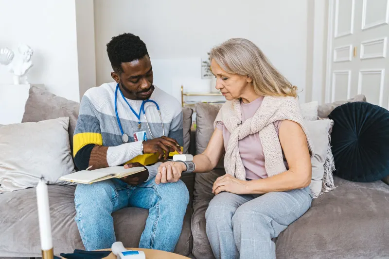 Healthcare professional checking an elderly woman’s blood pressure